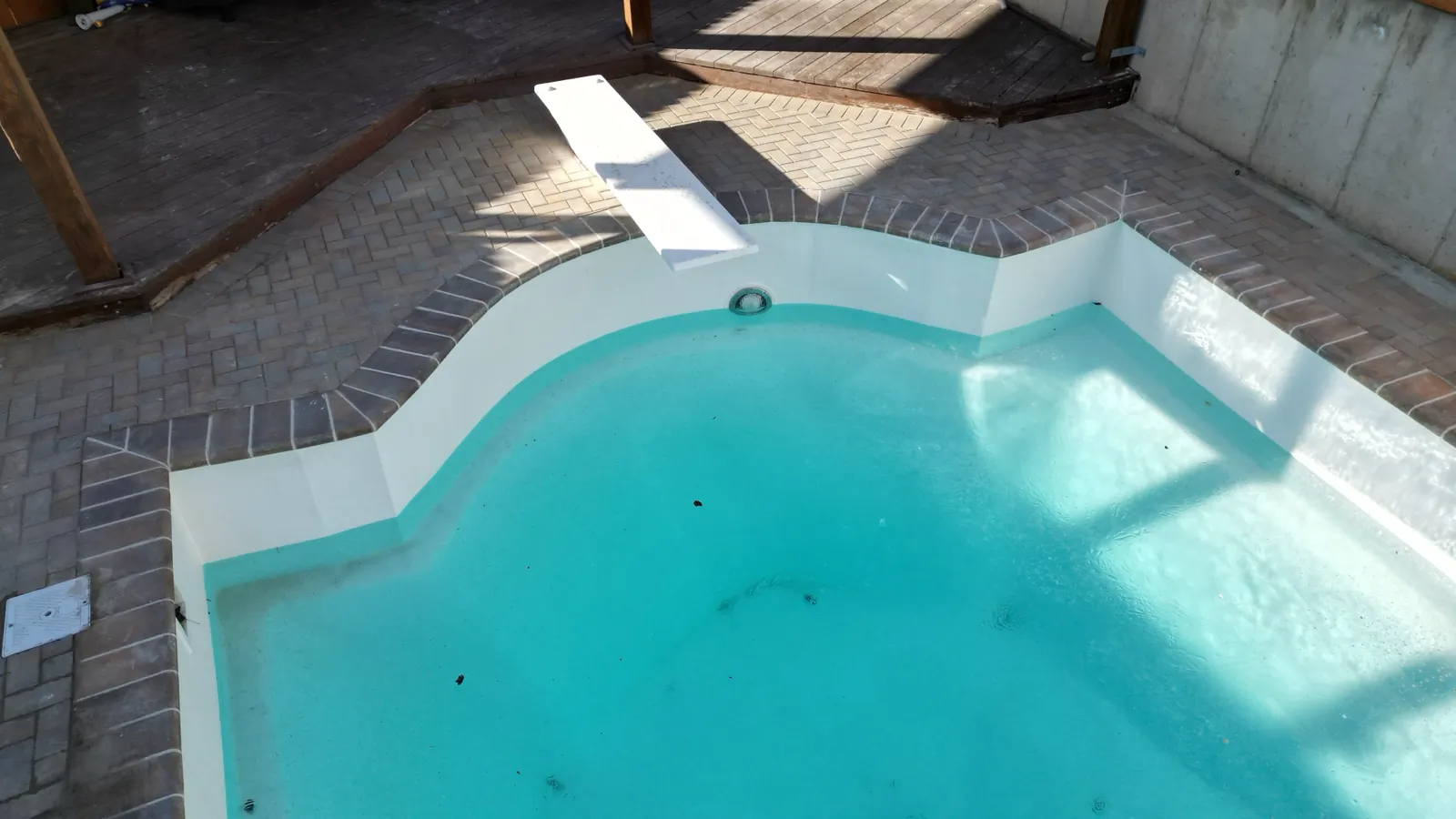 Pool with a diving board and brick paver deck