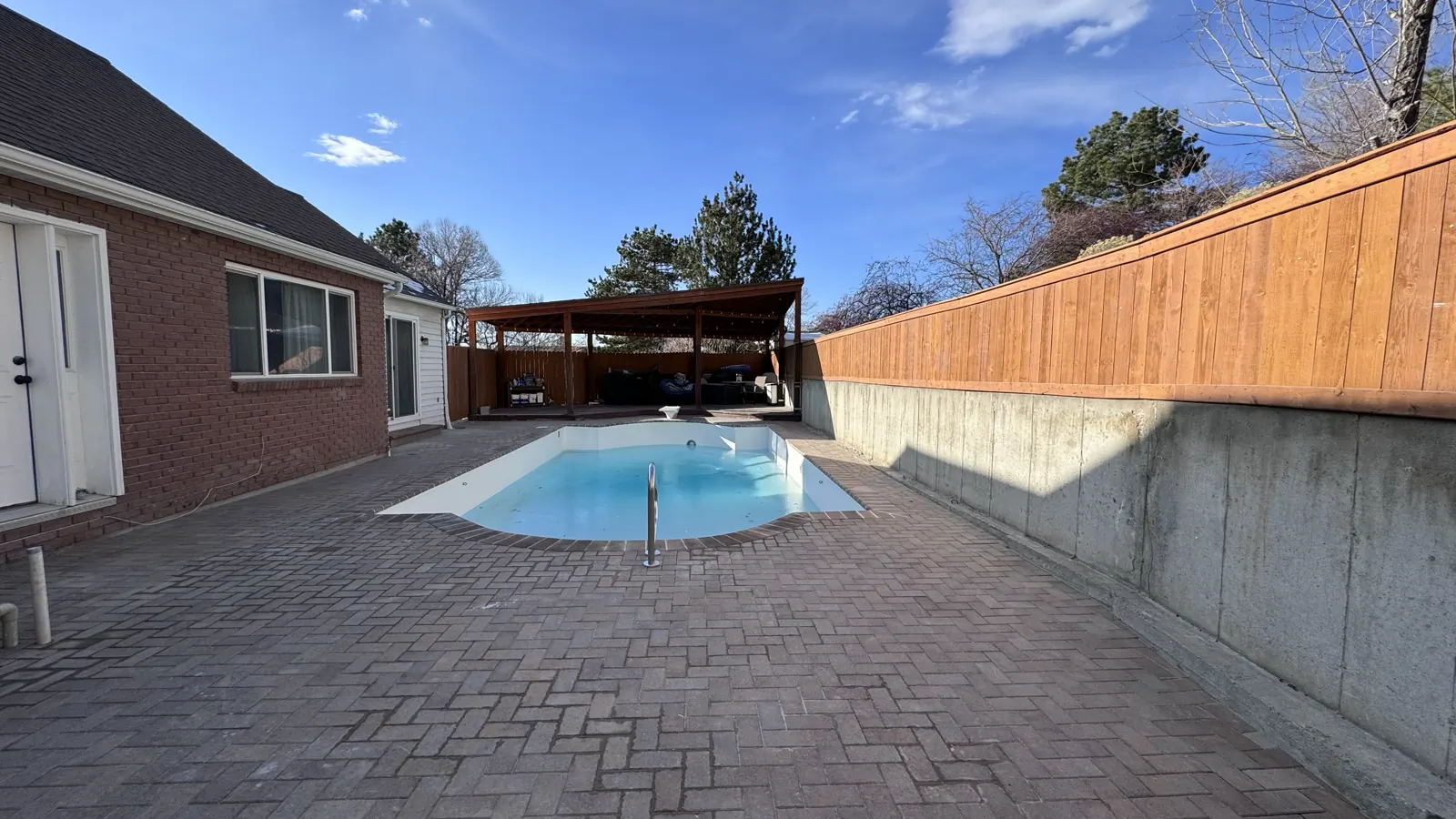 Finished backyard pool with paver deck and covered pergola
