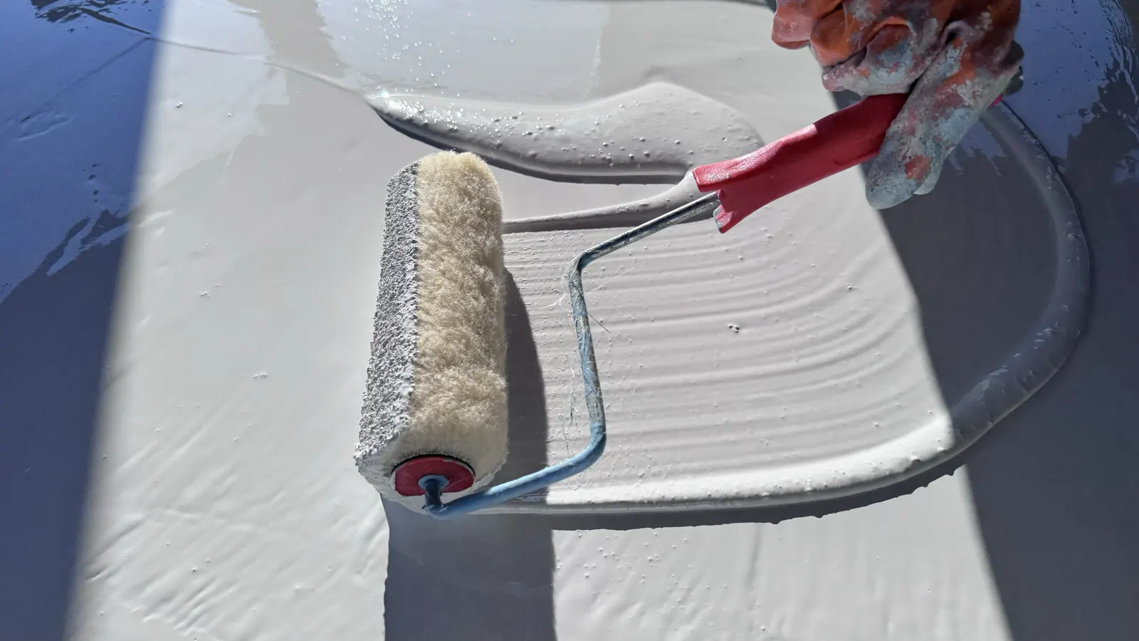 Close-up of a roller spreading pool finish